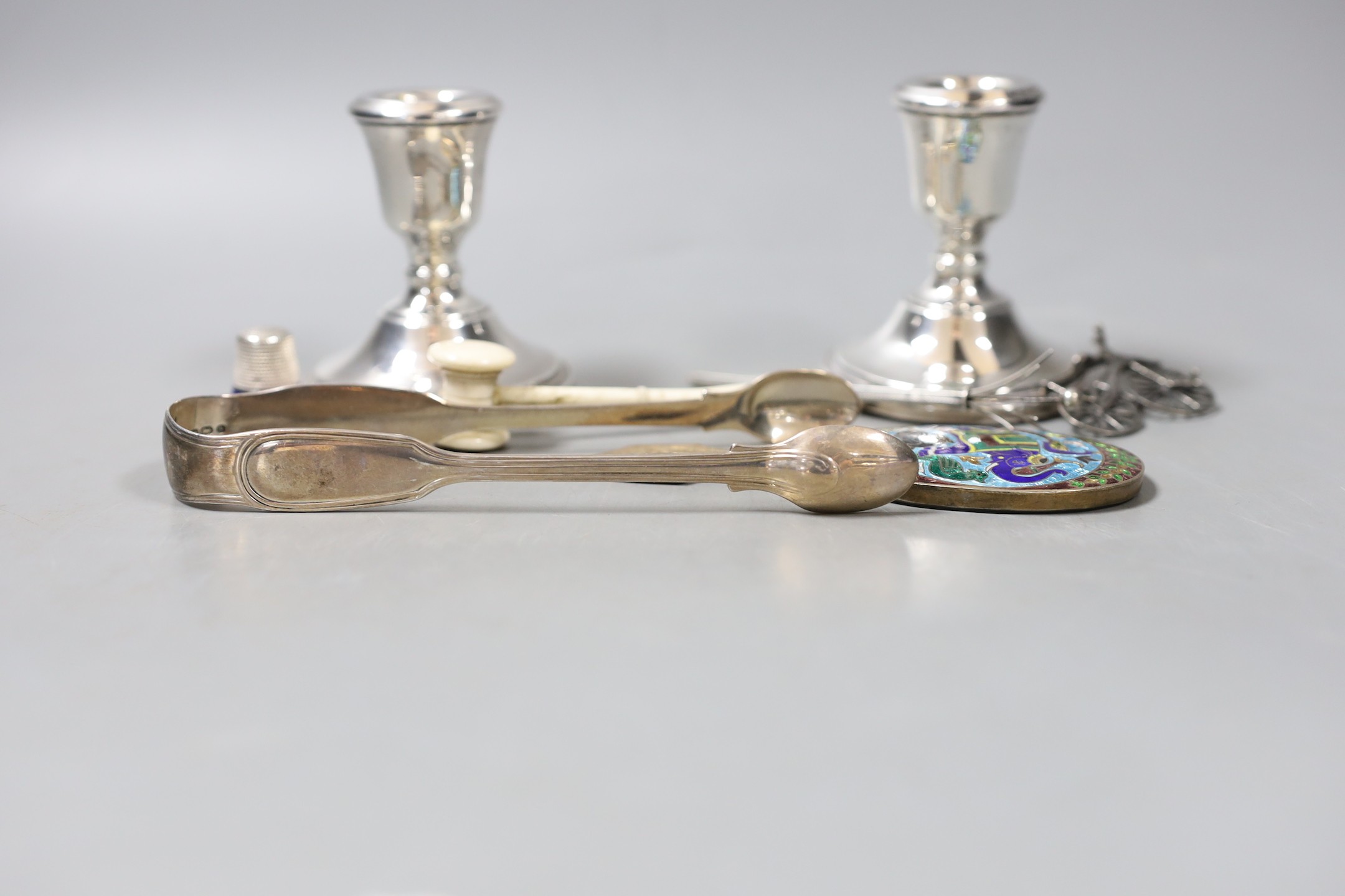 A group of mixed silver, to include sugar tongs, a pair of candlesticks, an Indian silver enamel mirror, a miniature bone gavel and other items